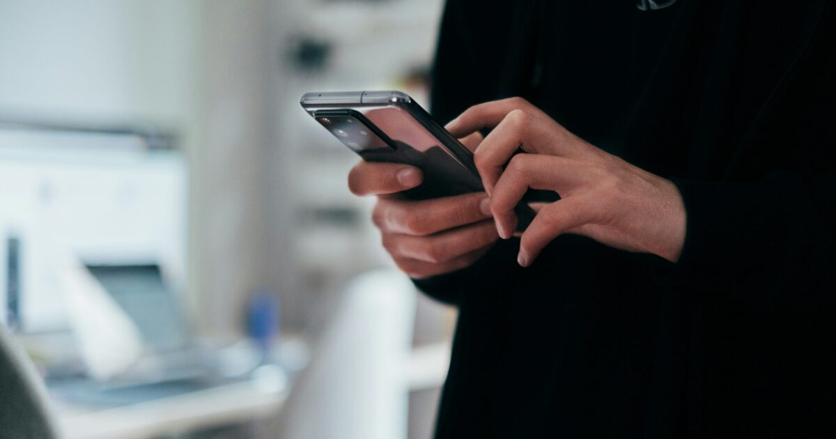 Close-up of a person using a smartphone powered by a business data SIM for temporary internet connectivity.